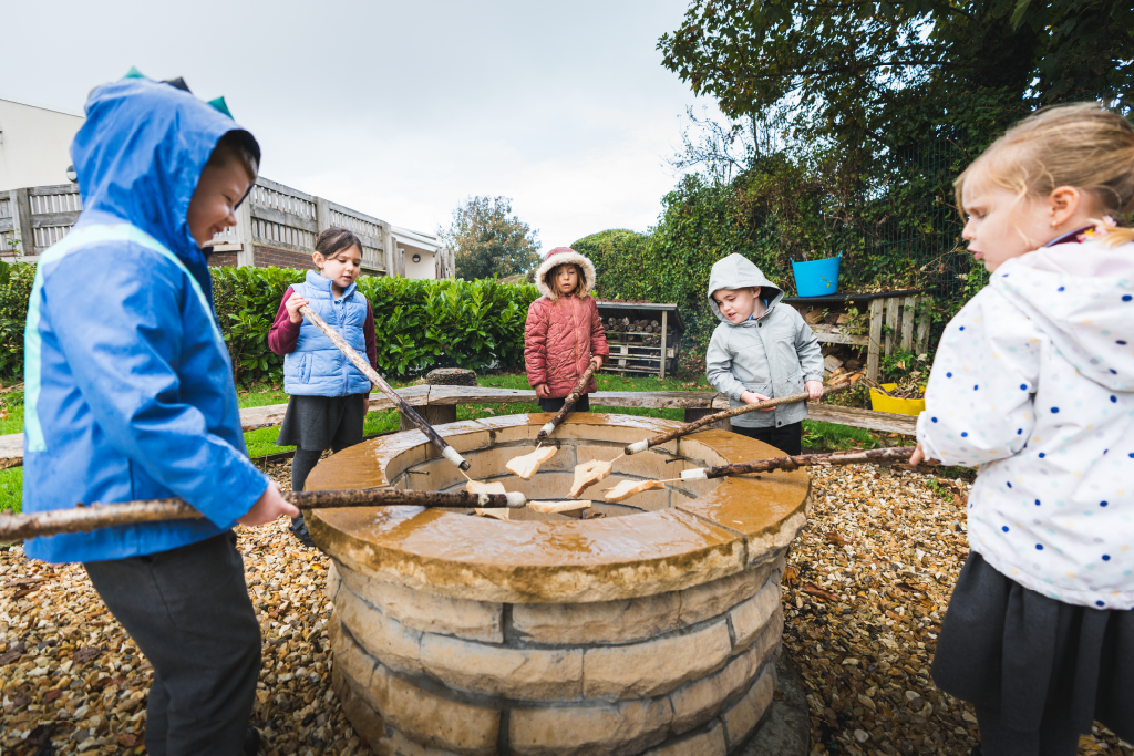 Pupils around the fire pit toasting bread Pupils around the fire pit toasting bread